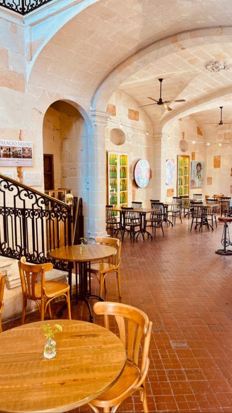 Interior de un café de Ciutadella con mesas de madera y bóvedas de piedra