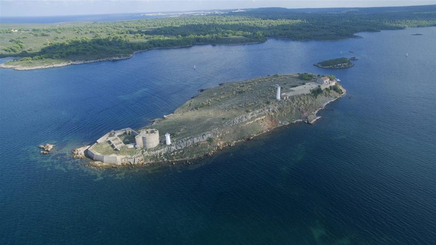 Illa de ses Sargantanes con su torre y construcciones en la bahía de Fornells, Menorca
