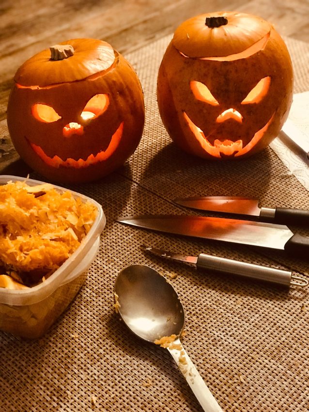 Dos calabazas talladas e iluminadas sobre una mesa