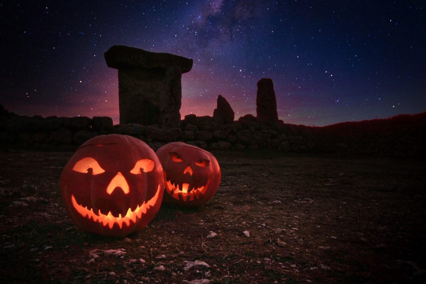 Calabazas iluminadas con una taula de Menorca bajo un cielo estrellado