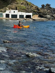 A kayaker explores the clear waters of a rocky cove in Menorca. A kayaker explores the clear waters of a rocky cove in Menorca.