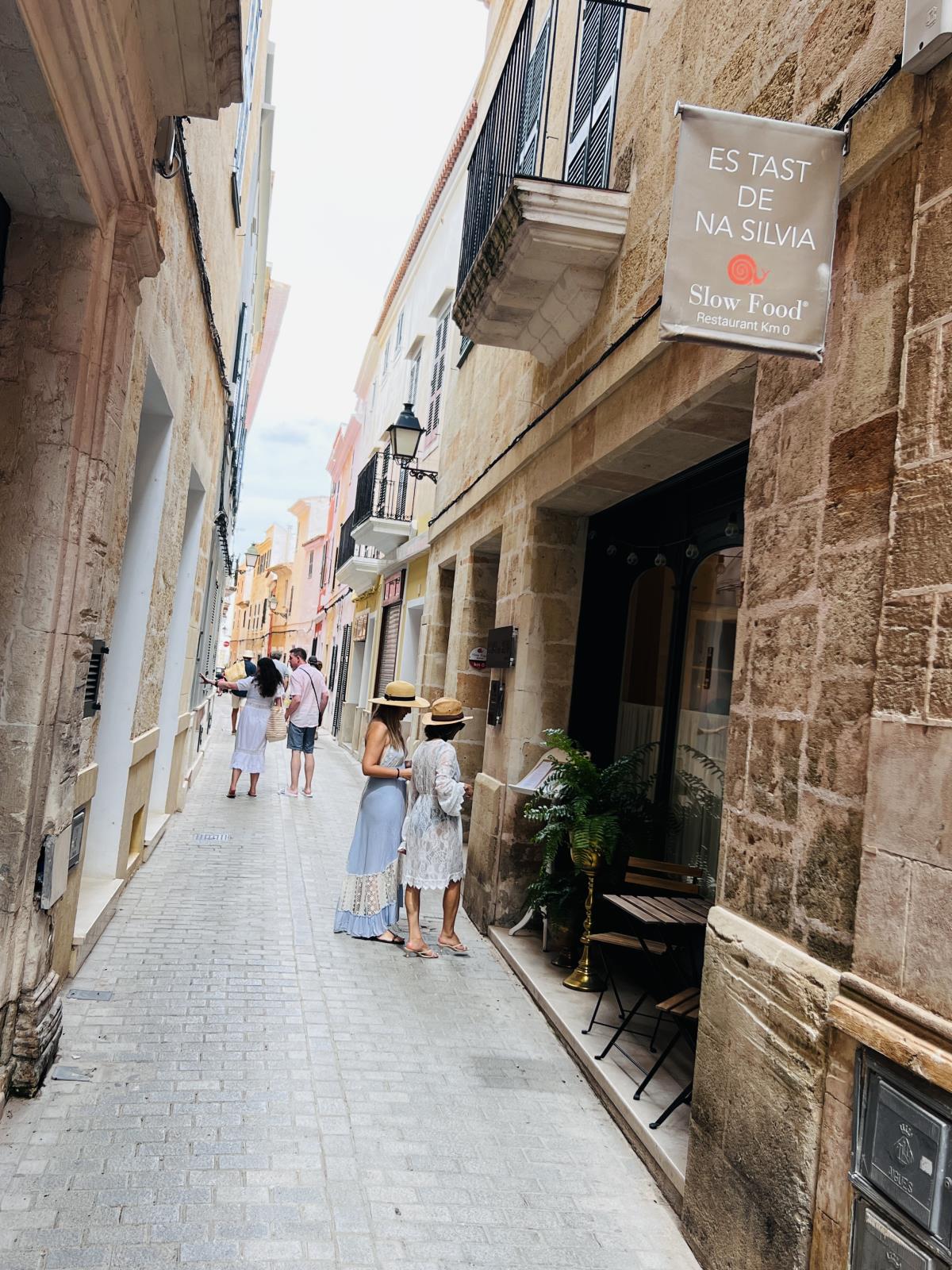 Pedestrians and a restaurant on a narrow street in Ciutadella old town
