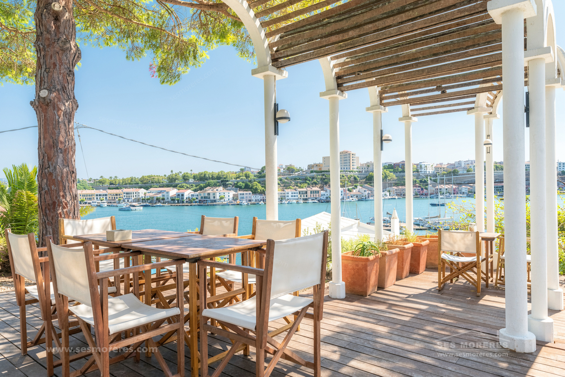 Terrasse ombragée avec pergola en bois donnant sur le port de Mahón