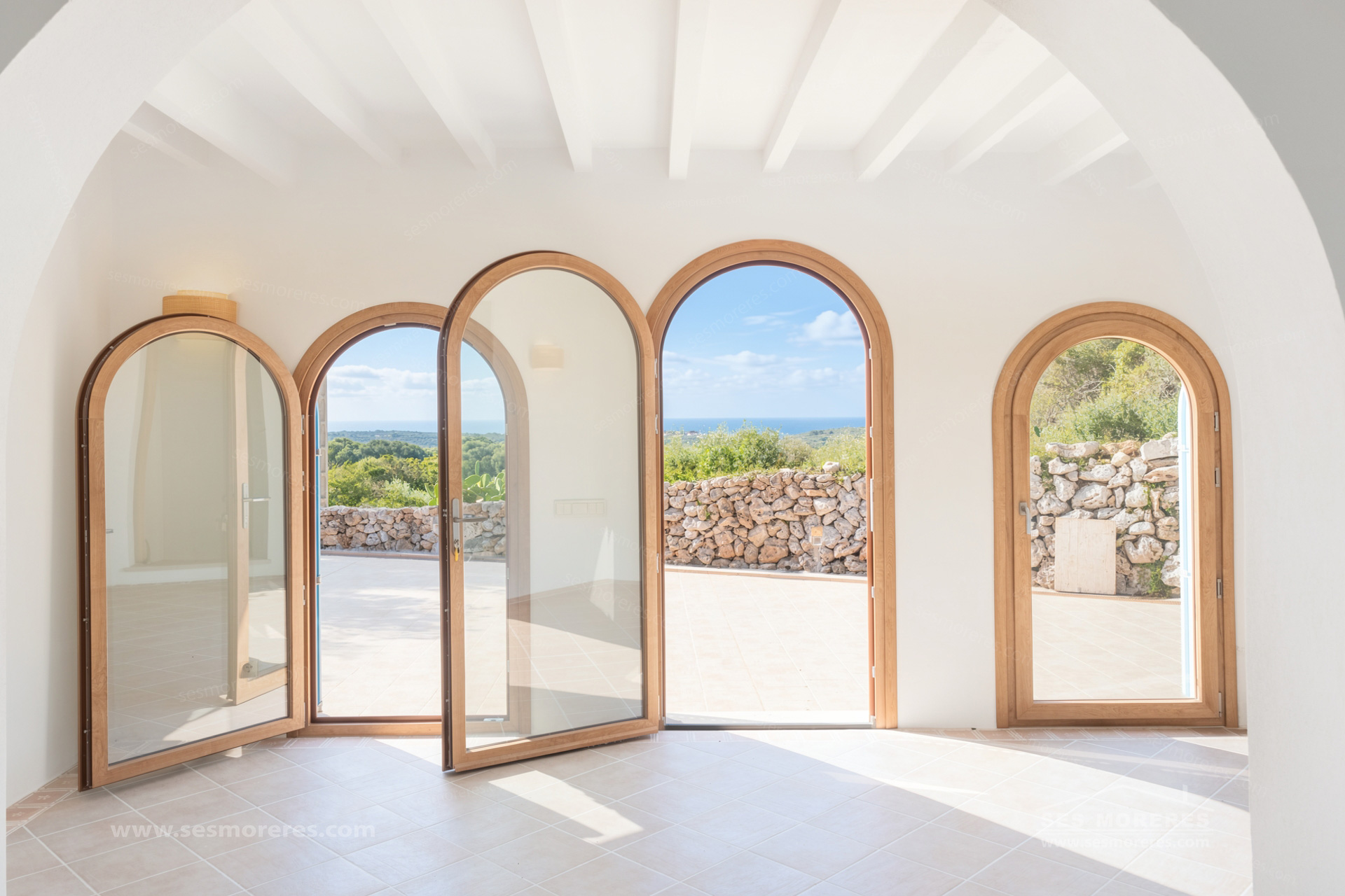 Fenêtres cintrées en bois apportant de la lumière naturelle dans une maison à Minorque